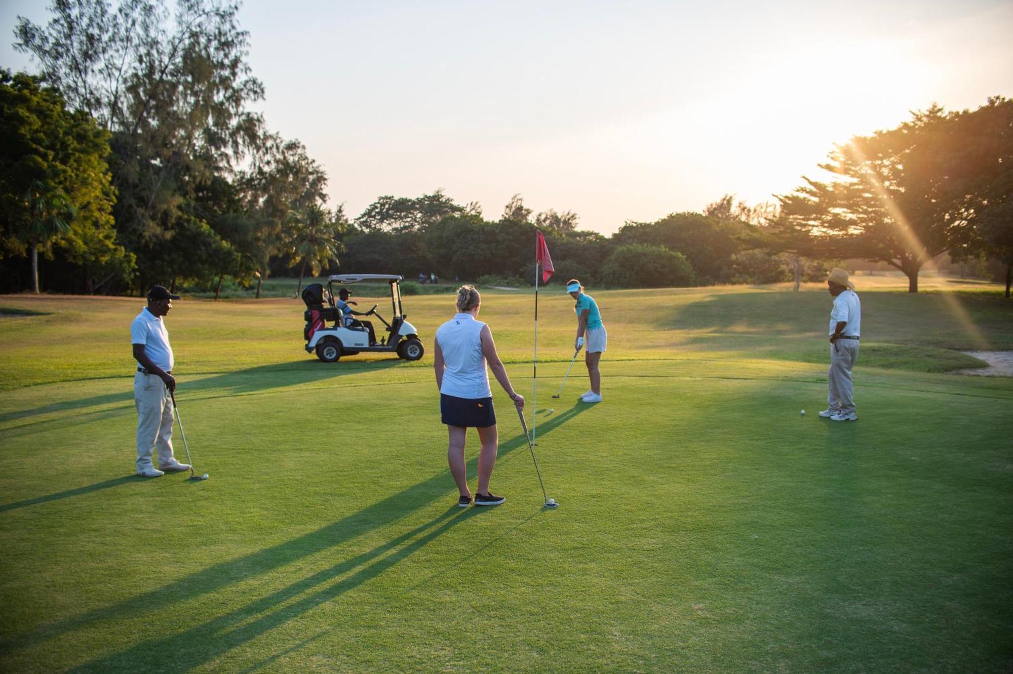 Diamonds Leisure Beach & Golf Resort Диани-Бич Экстерьер фото Golfers putting on the 18th green at the Royal Pines Resort